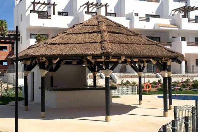 Pérgola poligonal con cubierta de brezo para piscina comunitaria